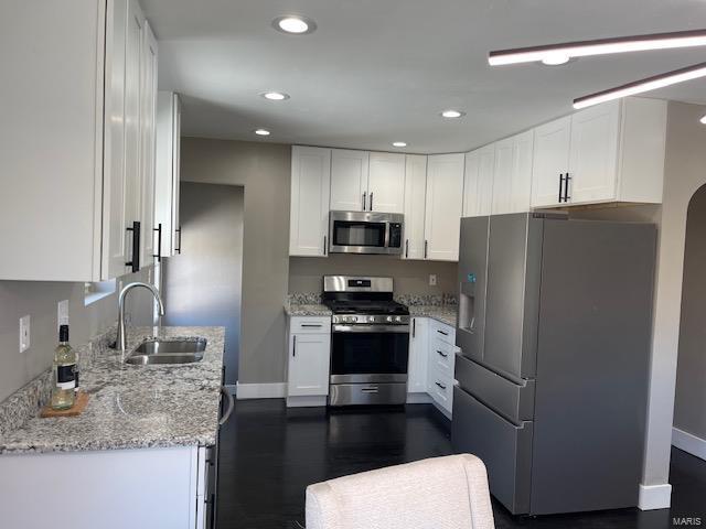 kitchen with white cabinetry, sink, stainless steel appliances, and light stone countertops