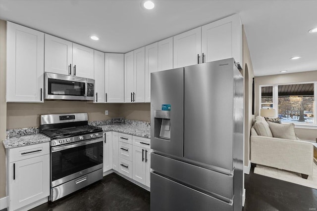 kitchen featuring stainless steel appliances, white cabinets, and light stone counters