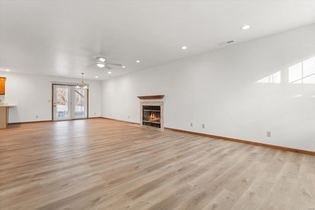 unfurnished living room featuring ceiling fan with notable chandelier and light hardwood / wood-style floors