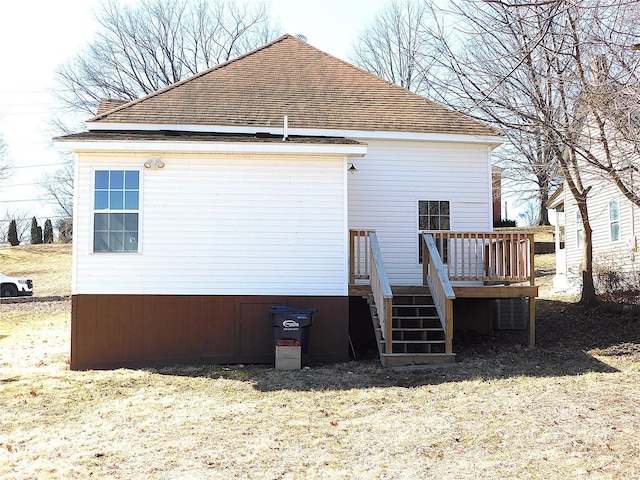 rear view of property with a deck, roof with shingles, and stairway