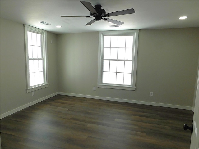 empty room with dark wood-style floors, recessed lighting, visible vents, and baseboards