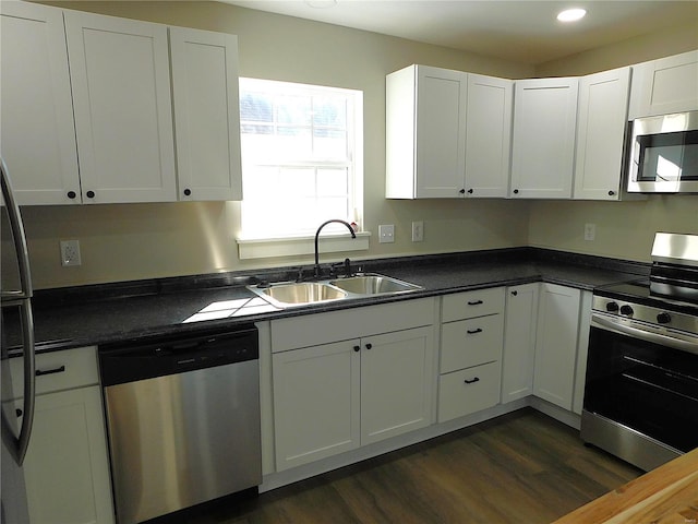 kitchen with dark countertops, dark wood-style flooring, stainless steel appliances, and a sink