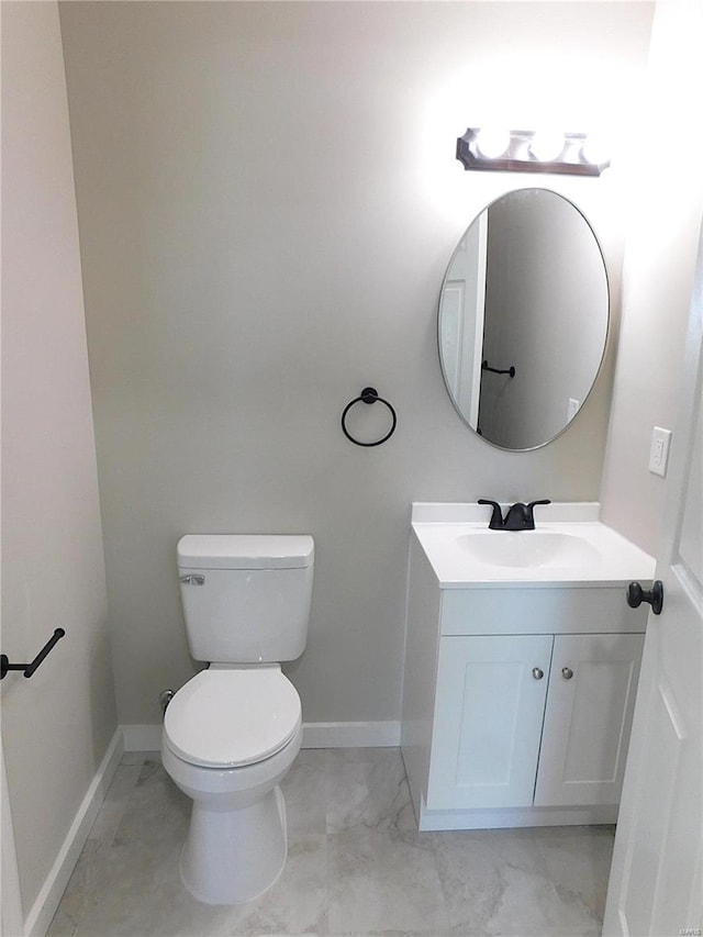 bathroom featuring toilet, marble finish floor, baseboards, and vanity