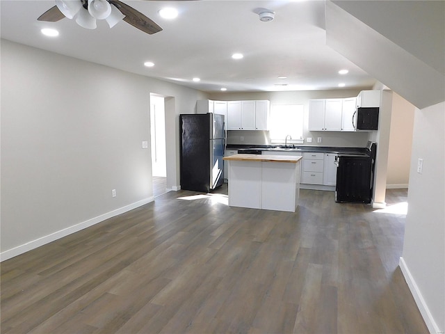 kitchen with dark wood finished floors, stainless steel appliances, white cabinetry, a sink, and baseboards