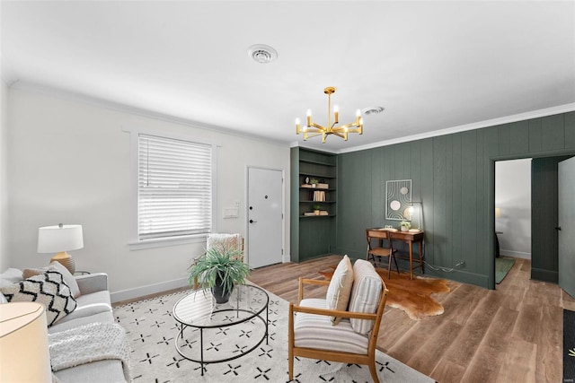 living room with hardwood / wood-style floors, crown molding, built in features, and a chandelier