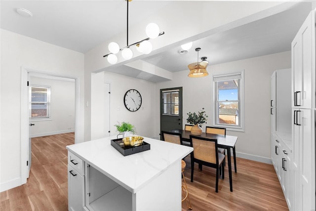 kitchen featuring a kitchen island, white cabinets, light hardwood / wood-style floors, and decorative light fixtures