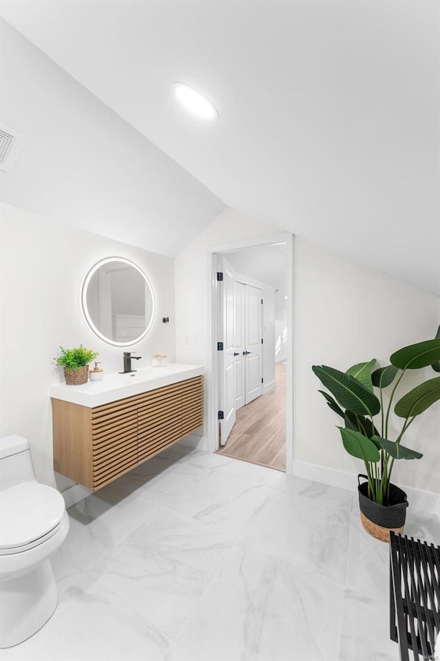 bathroom featuring vanity, lofted ceiling, and toilet