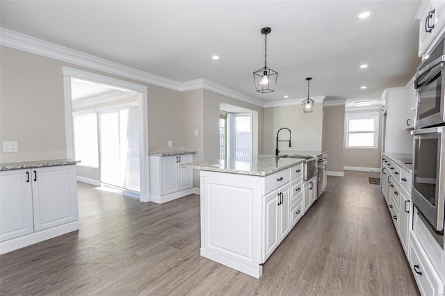 kitchen featuring white cabinetry, sink, a kitchen island with sink, and hanging light fixtures