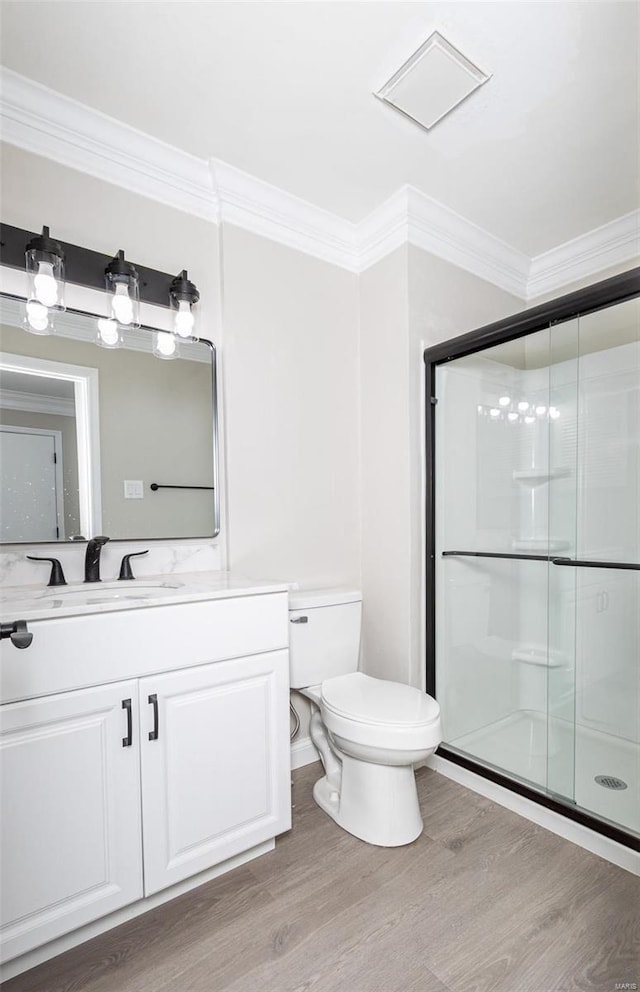 bathroom with walk in shower, toilet, crown molding, vanity, and hardwood / wood-style flooring