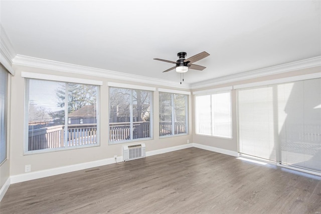 unfurnished sunroom with ceiling fan and a wall unit AC