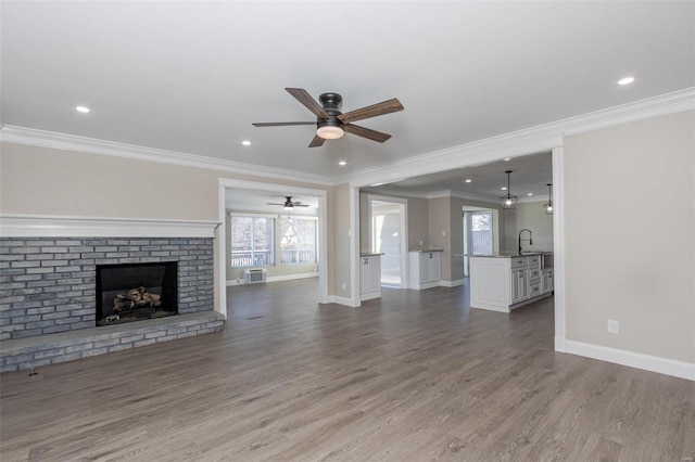 unfurnished living room featuring sink, ceiling fan, ornamental molding, light hardwood / wood-style floors, and a brick fireplace