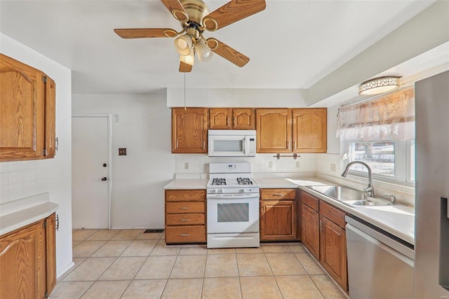 kitchen featuring sink, white appliances, light tile patterned floors, ceiling fan, and backsplash