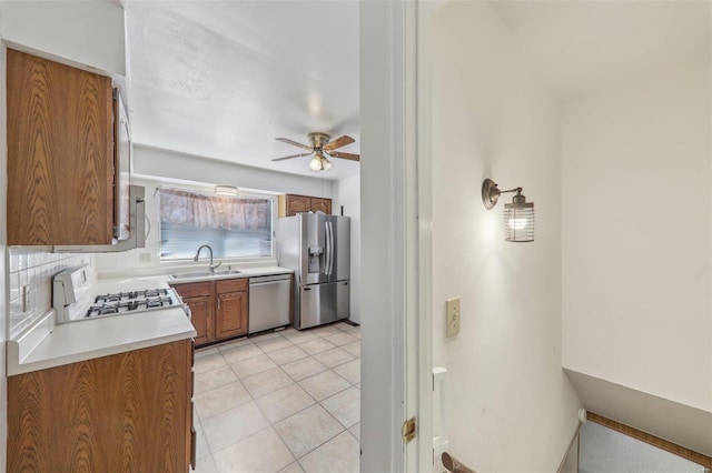 kitchen with light tile patterned flooring, tasteful backsplash, sink, ceiling fan, and stainless steel appliances