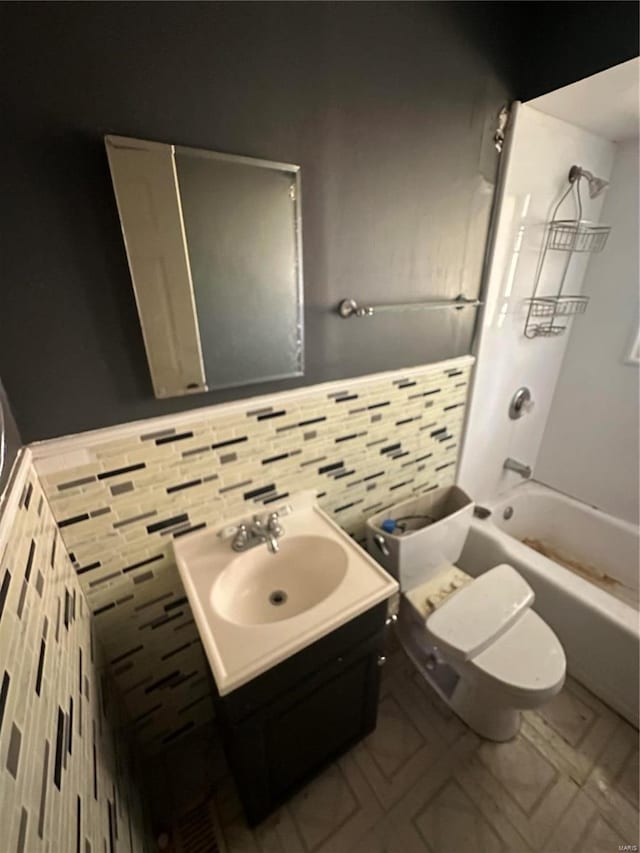 full bathroom featuring toilet, tasteful backsplash, vanity, and  shower combination