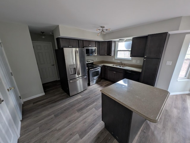 kitchen with wood-type flooring, a kitchen island, sink, and stainless steel appliances