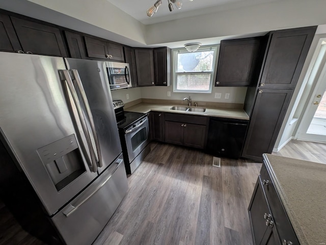 kitchen featuring sink, stainless steel appliances, dark brown cabinets, and hardwood / wood-style floors