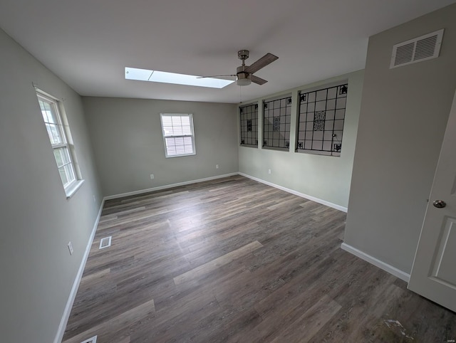 spare room with ceiling fan, dark hardwood / wood-style flooring, and a skylight