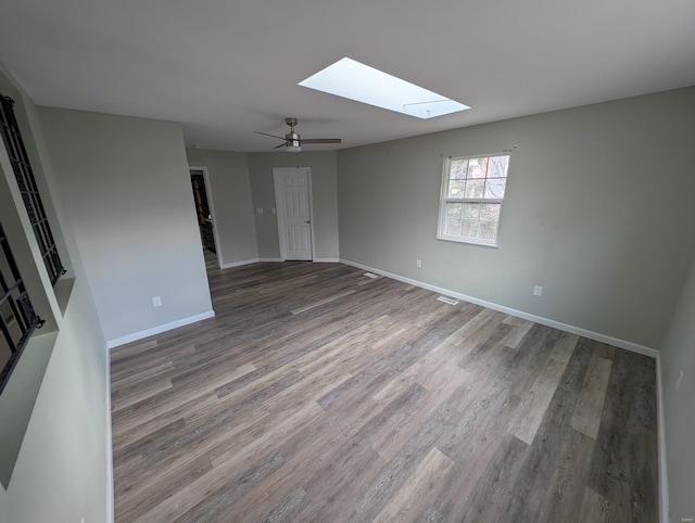 unfurnished room featuring wood-type flooring, ceiling fan, and a skylight