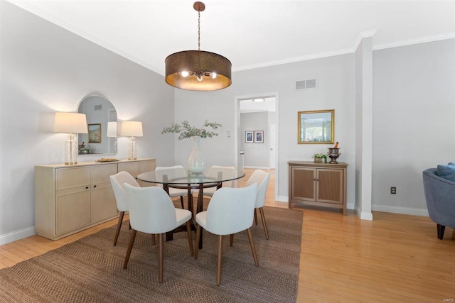 dining area with visible vents, light wood-style flooring, crown molding, and baseboards