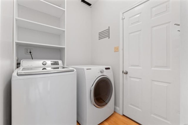 laundry room with laundry area, light wood finished floors, and washer and dryer