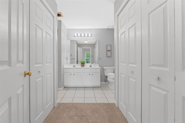 bathroom with double vanity, tile patterned flooring, baseboards, a closet, and toilet