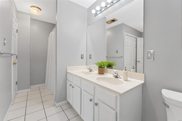 bathroom featuring double vanity, a sink, tile patterned floors, and toilet