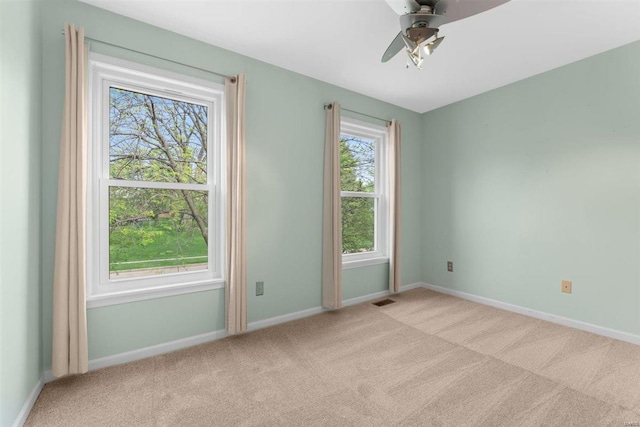 spare room with carpet floors, a ceiling fan, baseboards, and visible vents