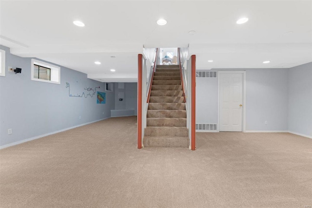 basement featuring baseboards, light carpet, and recessed lighting