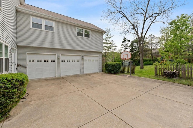 garage with fence and concrete driveway