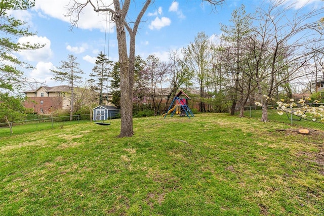 view of yard with a storage shed, an outbuilding, a fenced backyard, and a playground