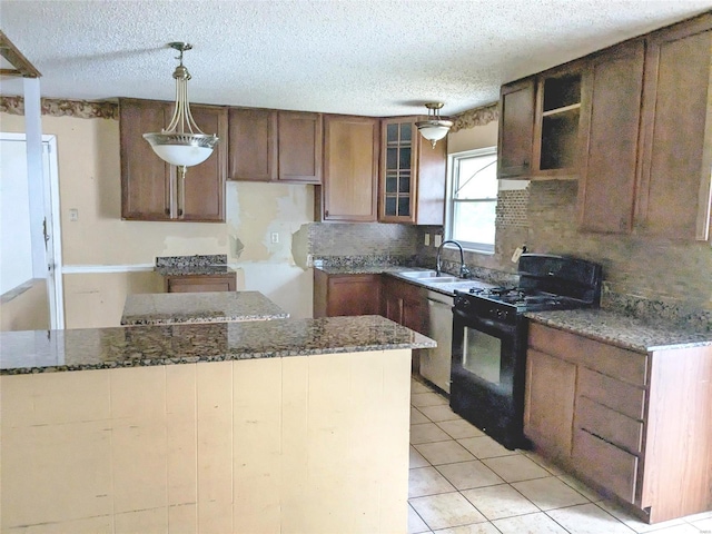 kitchen with a textured ceiling, dark stone counters, sink, hanging light fixtures, and black gas range