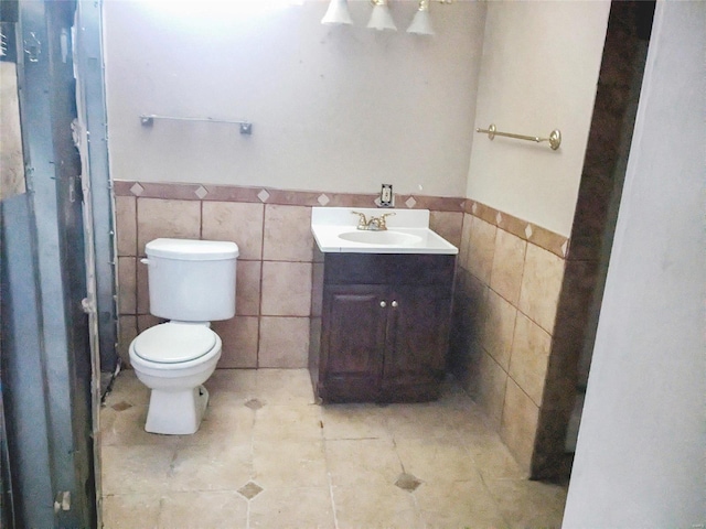 bathroom featuring toilet, vanity, and tile walls