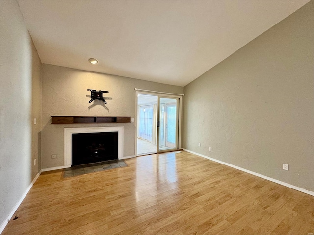 unfurnished living room with wood-type flooring and vaulted ceiling