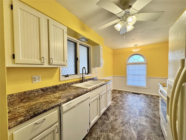 kitchen featuring ceiling fan, sink, white appliances, and dark stone counters