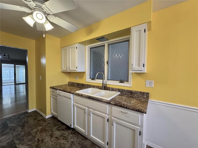 kitchen with dishwasher, sink, dark stone countertops, white cabinets, and ceiling fan