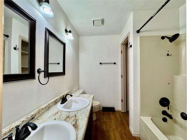 full bathroom featuring hardwood / wood-style flooring, washtub / shower combination, vanity, and toilet