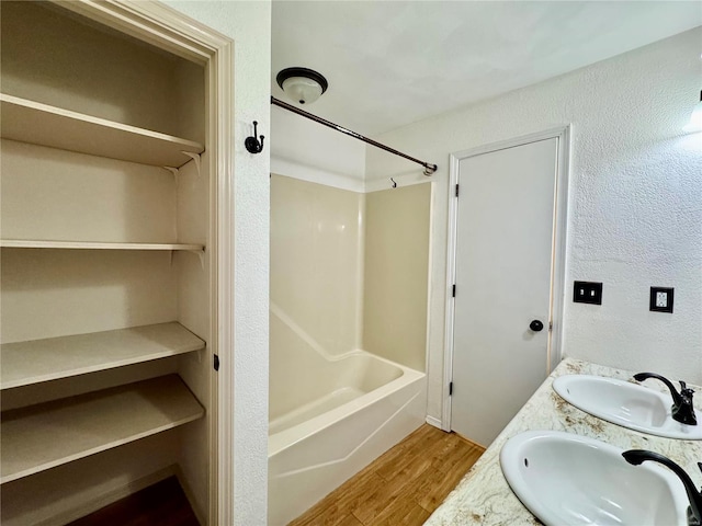 bathroom featuring hardwood / wood-style flooring, vanity, and washtub / shower combination