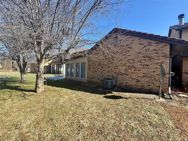 view of side of home with a lawn and central air condition unit