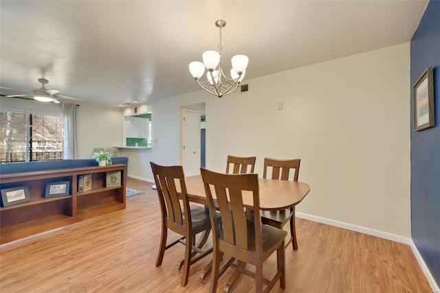 dining room featuring ceiling fan with notable chandelier and light hardwood / wood-style floors