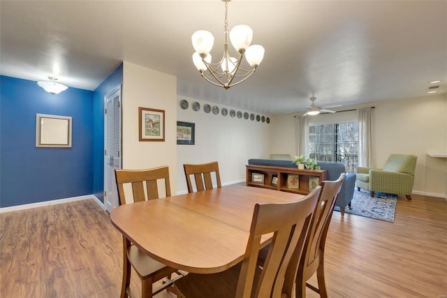 dining room featuring ceiling fan with notable chandelier and light hardwood / wood-style flooring