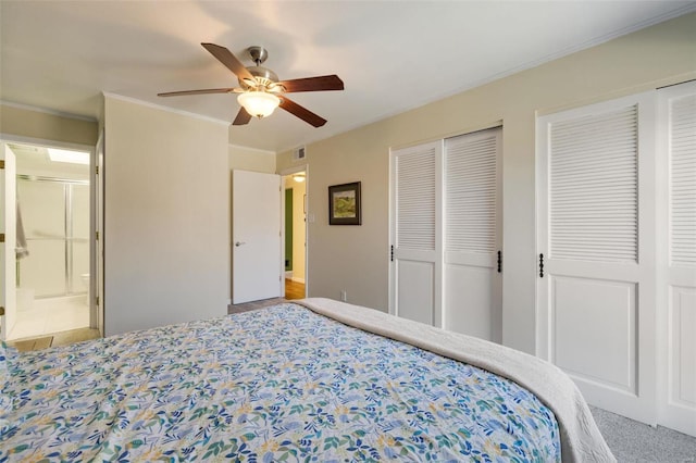 carpeted bedroom featuring crown molding, two closets, and ceiling fan