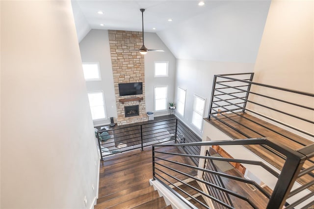 staircase featuring a fireplace, hardwood / wood-style flooring, ceiling fan, and a wealth of natural light