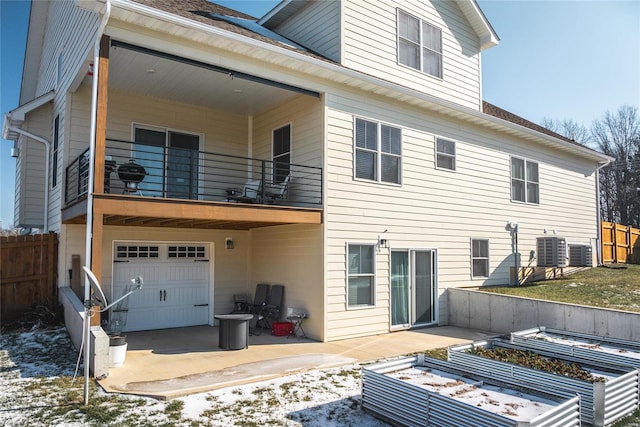 snow covered property featuring a balcony, a garage, and central AC