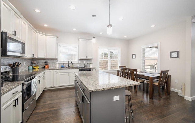 kitchen with white cabinets, a center island, appliances with stainless steel finishes, and pendant lighting