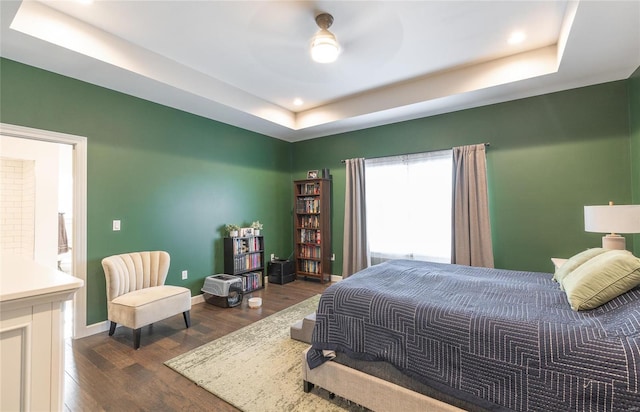 bedroom with ceiling fan, a raised ceiling, and dark hardwood / wood-style floors