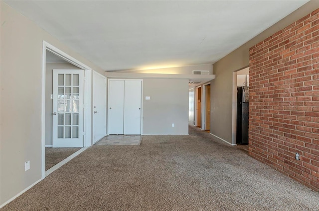 empty room with light carpet, lofted ceiling, and brick wall