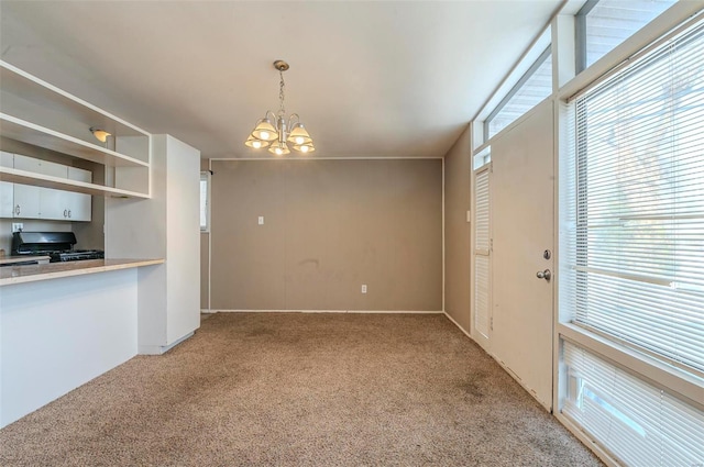 kitchen with an inviting chandelier, decorative light fixtures, light colored carpet, and range