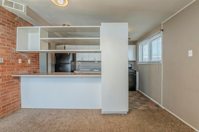 kitchen featuring white cabinetry, gas stove, black refrigerator, and carpet flooring