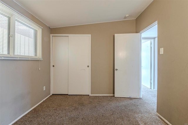 unfurnished bedroom featuring vaulted ceiling, carpet floors, and a closet