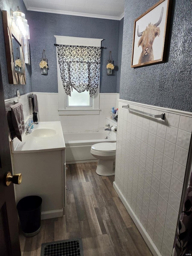 bathroom with vanity, a bathtub, toilet, hardwood / wood-style flooring, and crown molding